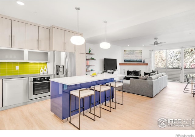 kitchen featuring a breakfast bar area, stainless steel appliances, tasteful backsplash, light wood-style floors, and a kitchen island