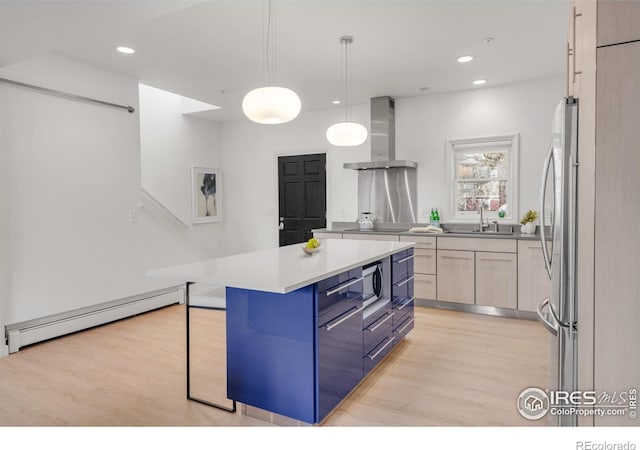 kitchen featuring a baseboard radiator, wall chimney exhaust hood, light countertops, blue cabinetry, and a sink