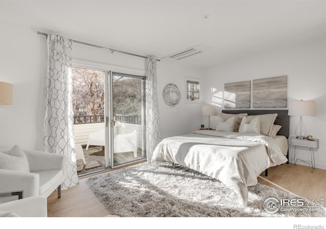 bedroom with access to outside and wood finished floors