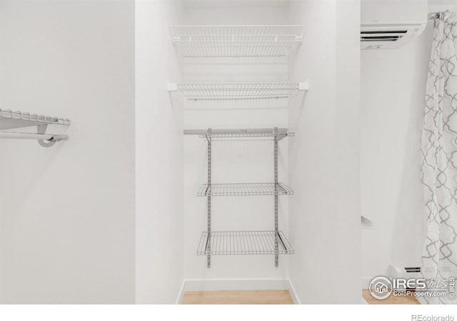 walk in closet featuring wood finished floors and a wall mounted AC