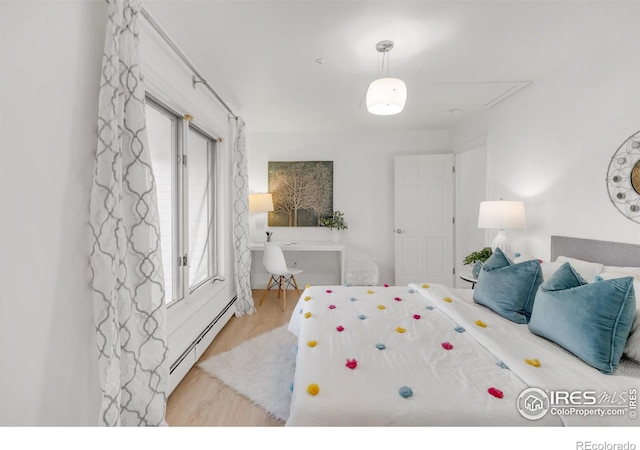 bedroom featuring a baseboard heating unit and wood finished floors