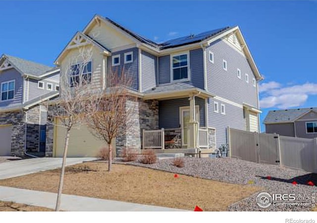 craftsman-style home featuring a porch, a garage, solar panels, fence, and concrete driveway