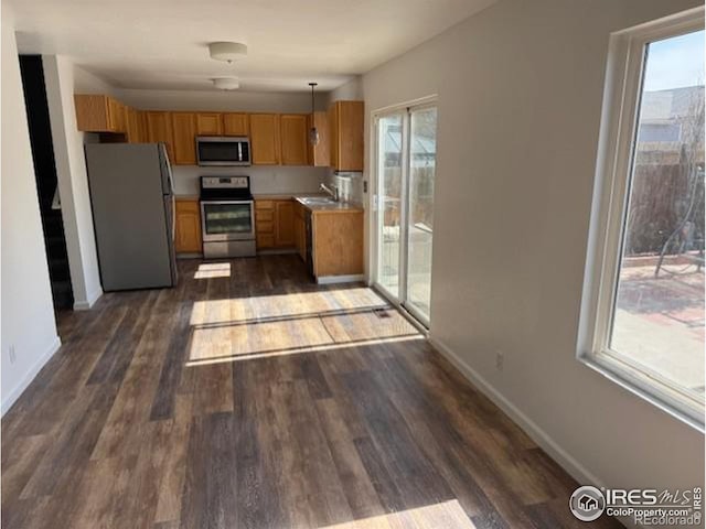 kitchen with baseboards, dark wood-style flooring, stainless steel appliances, light countertops, and a sink