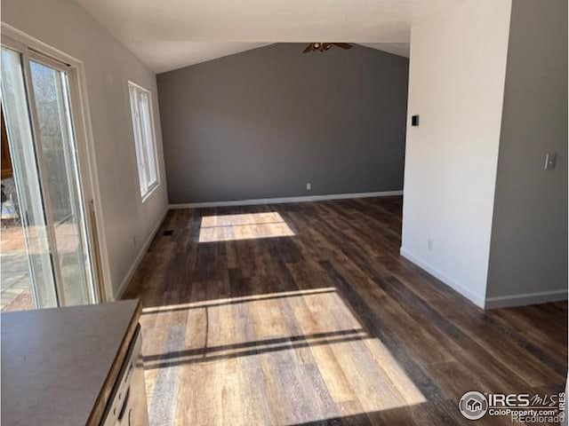 empty room featuring lofted ceiling, baseboards, and wood finished floors