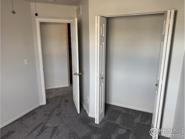 interior space with baseboards, visible vents, and dark colored carpet