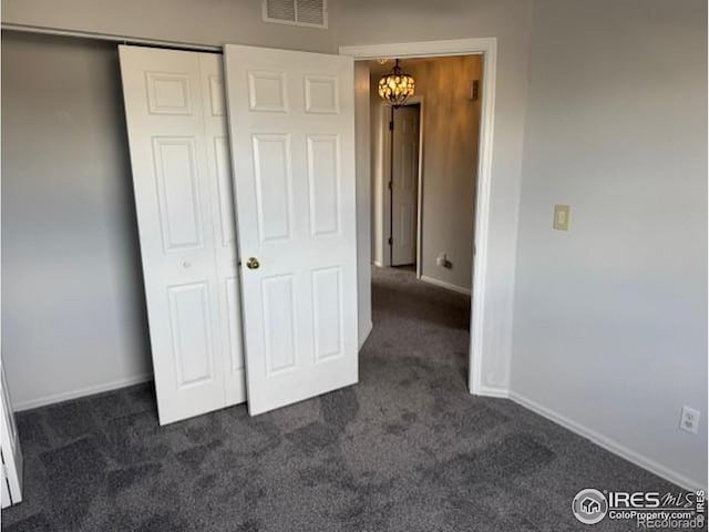 unfurnished bedroom featuring a closet, dark carpet, visible vents, and baseboards