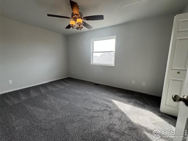 unfurnished room featuring dark colored carpet, a ceiling fan, and baseboards