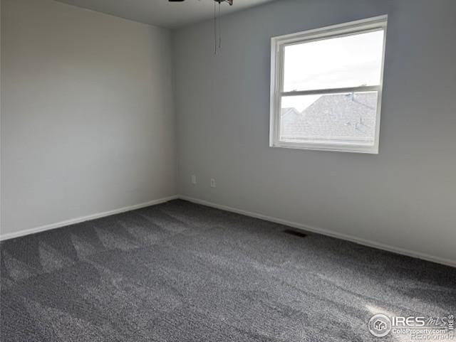 empty room featuring dark colored carpet, visible vents, and baseboards