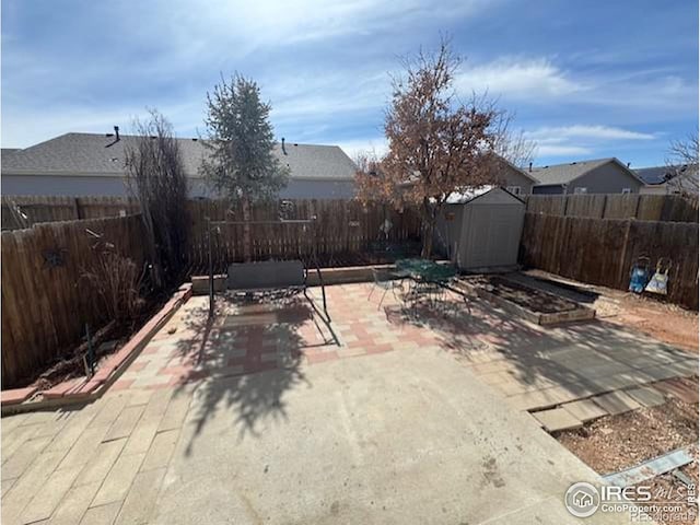 view of patio / terrace featuring an outbuilding, a storage unit, and a fenced backyard