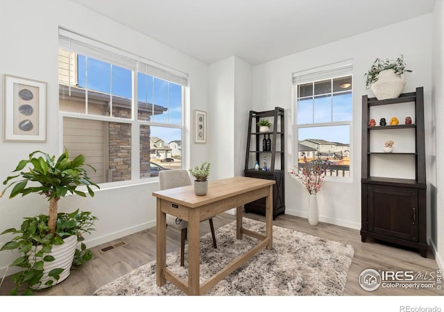 office with a healthy amount of sunlight, light wood-style floors, and baseboards