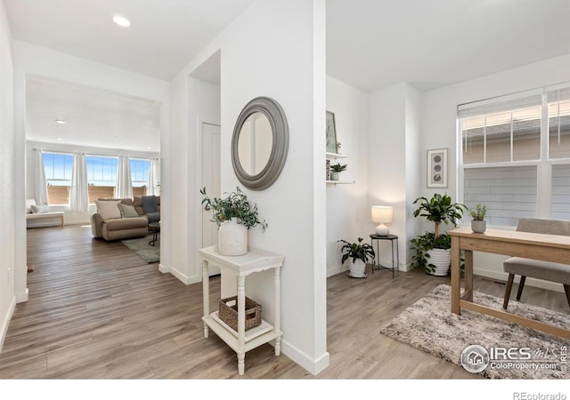 hallway with recessed lighting, light wood-style flooring, and baseboards