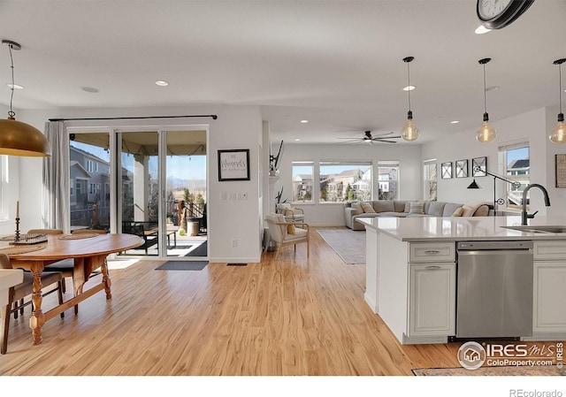 kitchen with pendant lighting, dishwasher, light wood-style flooring, and a sink