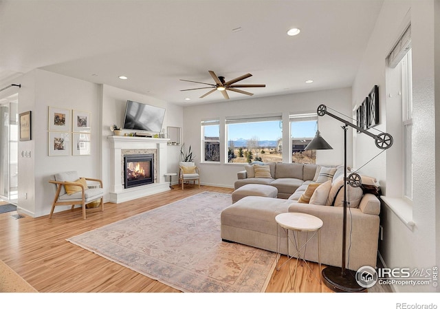 living room featuring recessed lighting, wood finished floors, a ceiling fan, baseboards, and a glass covered fireplace