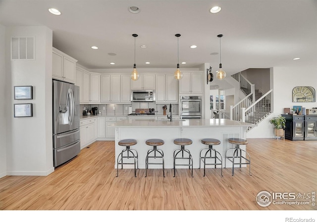 kitchen with stainless steel appliances, a sink, visible vents, and light wood-style floors