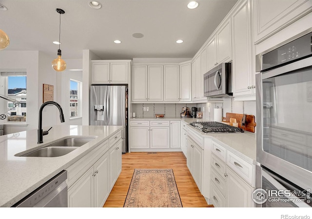 kitchen with pendant lighting, light countertops, appliances with stainless steel finishes, white cabinetry, and a sink