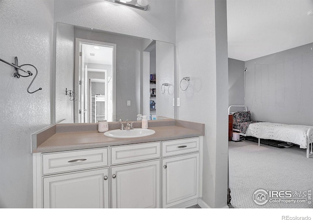 bathroom with ensuite bathroom, a textured wall, and vanity