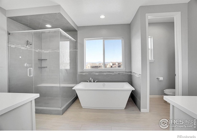 bathroom featuring a stall shower, a freestanding tub, vanity, and toilet