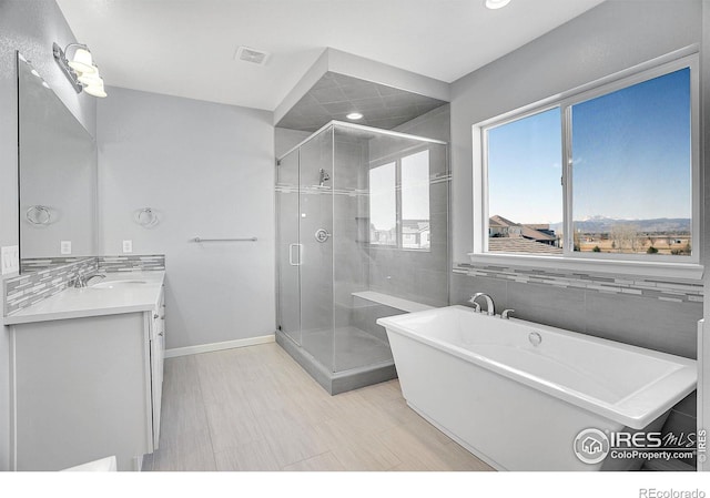 bathroom with a stall shower, visible vents, a freestanding bath, and vanity