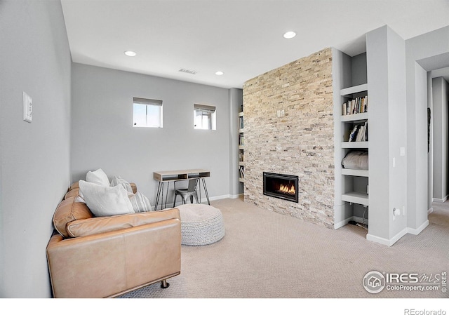 living area with built in features, carpet, a stone fireplace, and baseboards