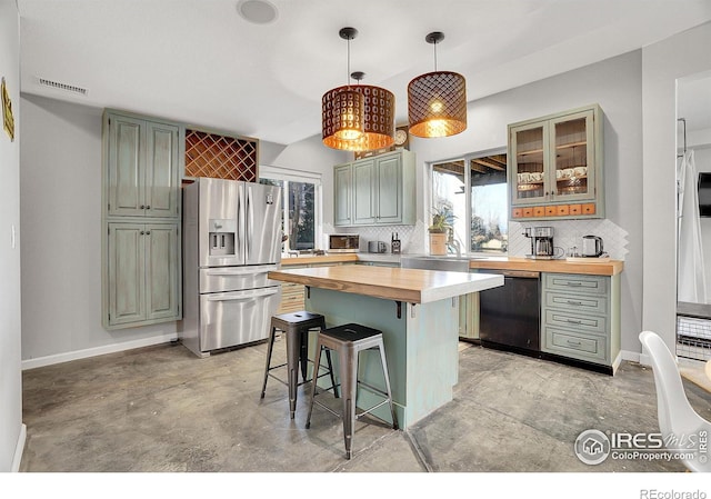 kitchen featuring wood counters, visible vents, a kitchen breakfast bar, dishwasher, and stainless steel fridge