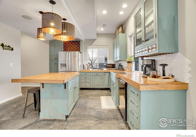 kitchen featuring black dishwasher, wooden counters, decorative backsplash, a kitchen island, and stainless steel fridge