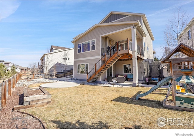 rear view of property with a trampoline, a yard, board and batten siding, a patio area, and a fenced backyard