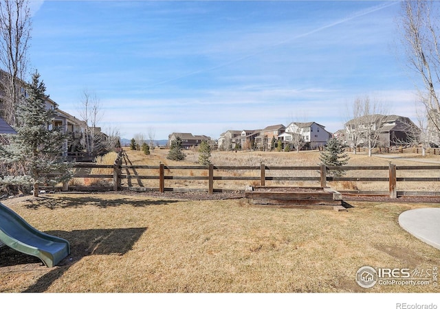 view of yard with a playground, fence, and a residential view