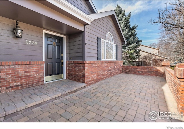 entrance to property with brick siding and a patio