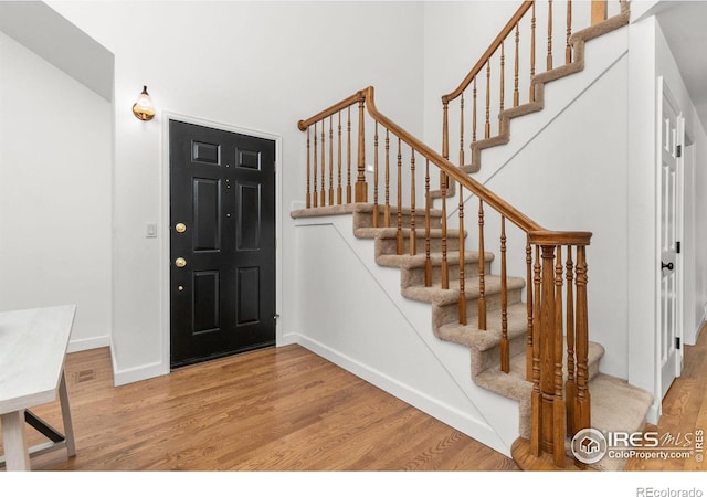 foyer entrance featuring stairway, wood finished floors, and baseboards