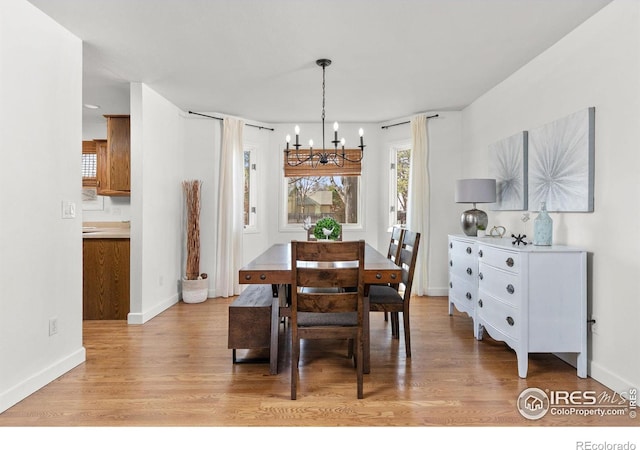 dining space with an inviting chandelier, baseboards, and light wood-style floors