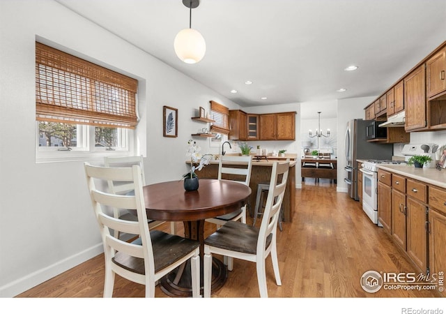 dining space featuring recessed lighting, light wood-style flooring, baseboards, and an inviting chandelier