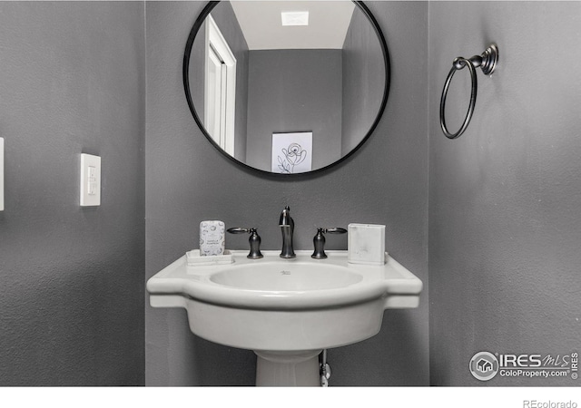 bathroom featuring a sink and a textured wall