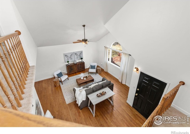 living area with lofted ceiling, wood finished floors, baseboards, and ceiling fan