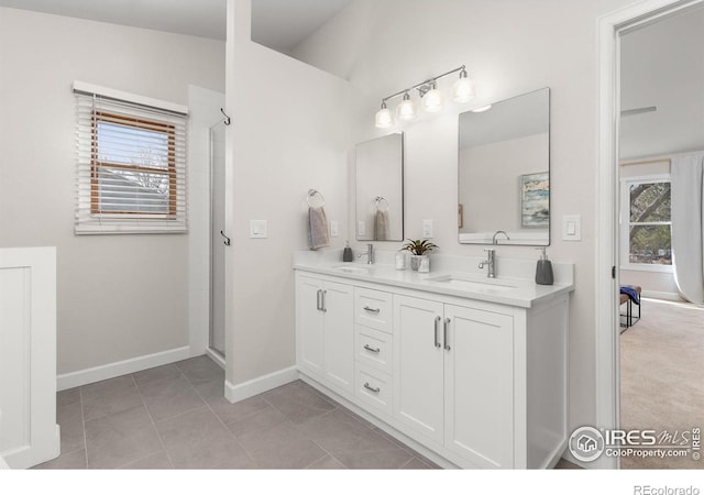 full bath featuring tile patterned floors, a shower with door, baseboards, and a sink