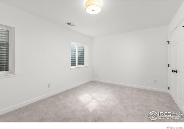 empty room featuring visible vents, baseboards, and carpet floors