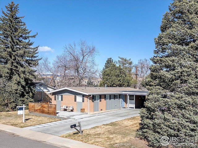 ranch-style home with concrete driveway, brick siding, and fence