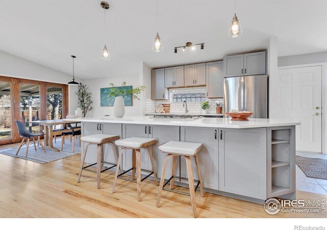 kitchen featuring stainless steel appliances, light countertops, gray cabinetry, and tasteful backsplash