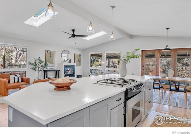 kitchen featuring stainless steel gas stove, lofted ceiling with skylight, open floor plan, and a wealth of natural light