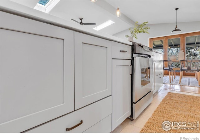 kitchen with lofted ceiling with skylight, decorative light fixtures, a ceiling fan, and light tile patterned flooring