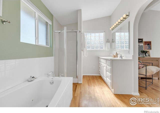 bathroom featuring a bath, wood finished floors, a shower stall, and vanity