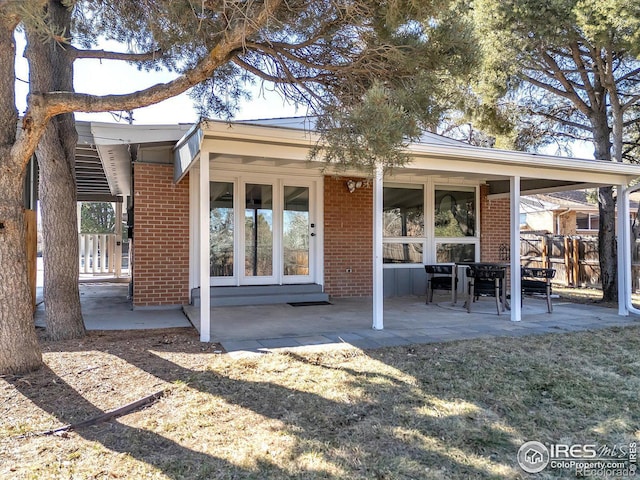 rear view of property with a patio area and brick siding