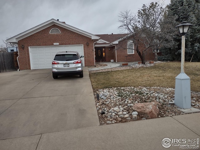 ranch-style house featuring a garage, concrete driveway, brick siding, and fence