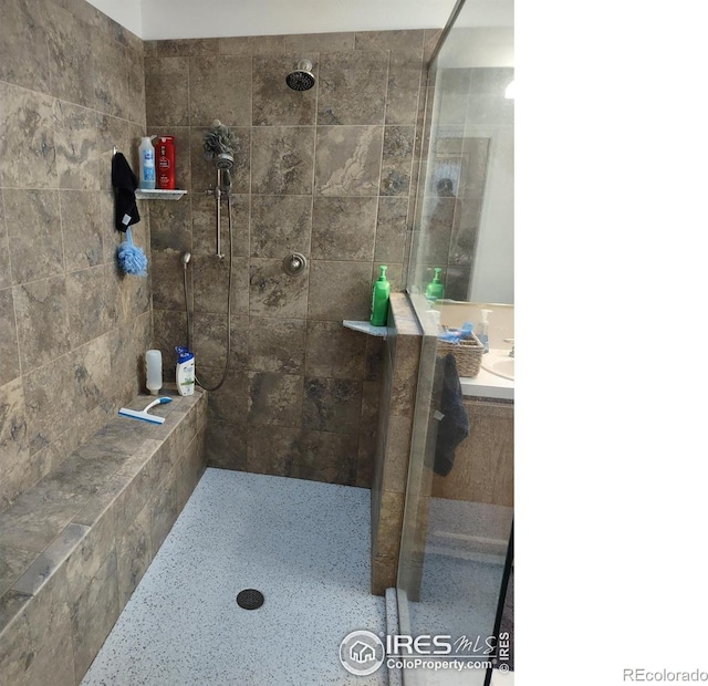 full bath featuring tiled shower and vanity