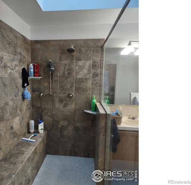 full bath featuring a tile shower and vanity