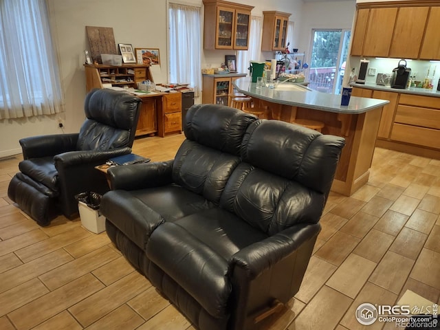 interior space with open floor plan, brown cabinetry, glass insert cabinets, and wood tiled floor