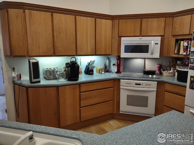 kitchen featuring brown cabinetry, light wood finished floors, and white appliances