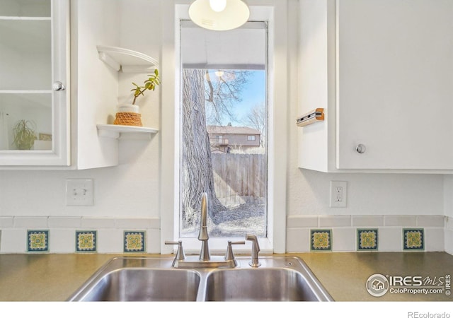 kitchen featuring a wealth of natural light, white cabinets, and a sink