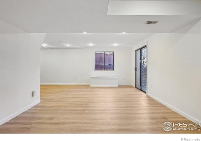 unfurnished room featuring light wood-type flooring, visible vents, and baseboards