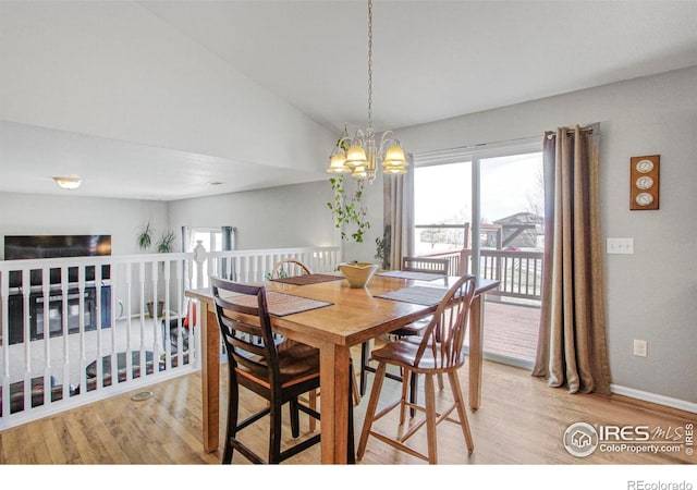 dining area featuring vaulted ceiling, a notable chandelier, baseboards, and wood finished floors