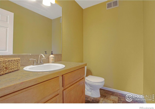 bathroom featuring visible vents, toilet, vanity, and baseboards